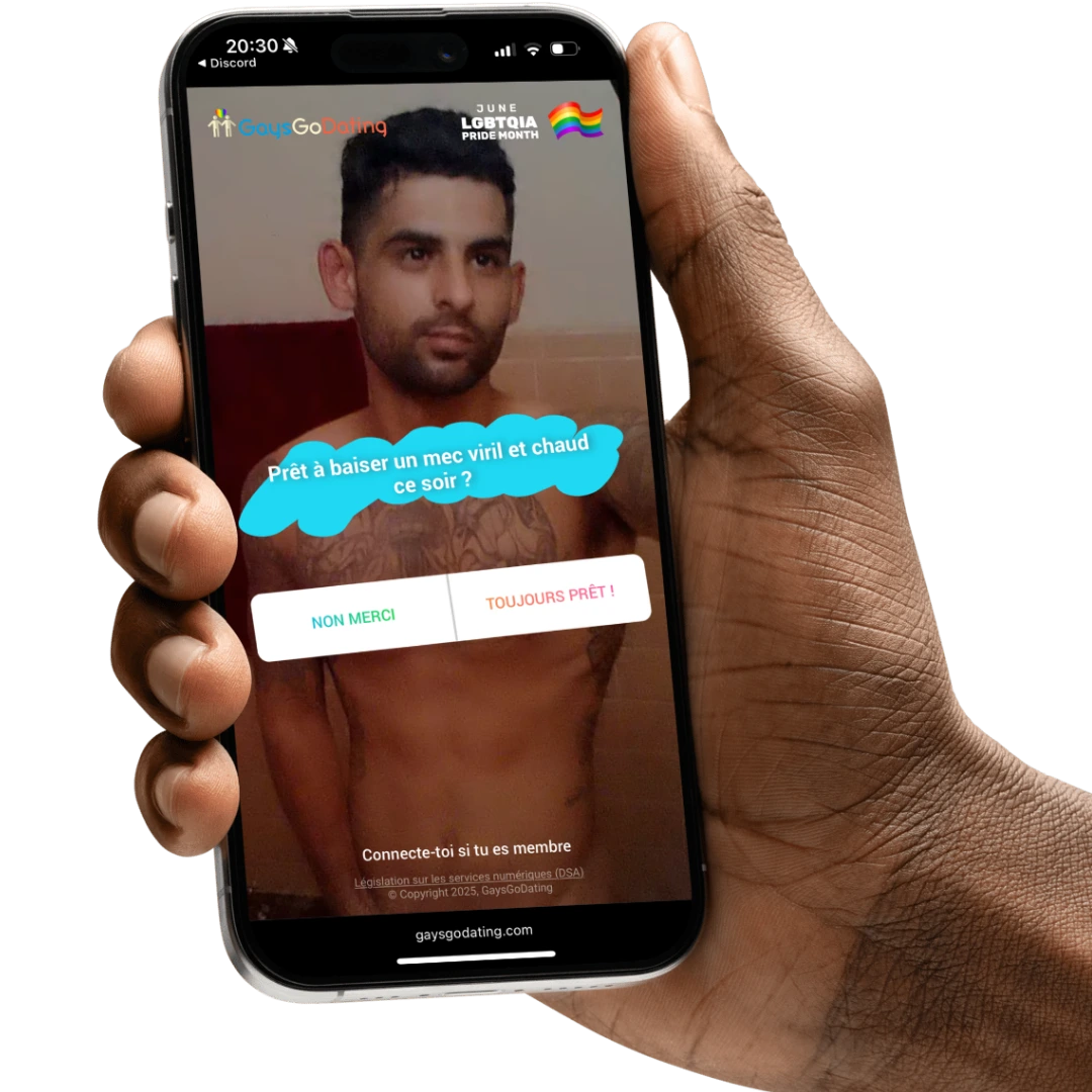 Main tenant un téléphone affichant un homme torse nu sur GuysGoDating avec le message 'Prêt à baiser un mec viril et chaud ce soir ?' et deux boutons : 'Non merci' et 'Toujours prêt !'.